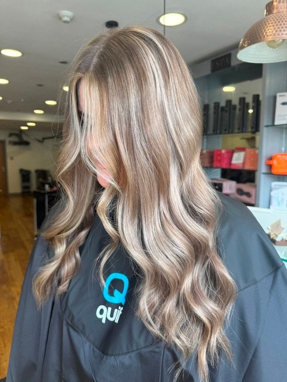 Lived-in bronde colour with soft blonde lengths on long waves, coloured at Thatchairs Hair & Body