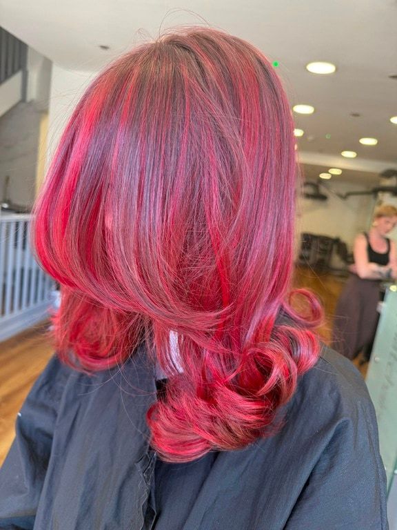 Vibrant red and pink colour with curled ends, coloured at Thatchairs Hair & Body