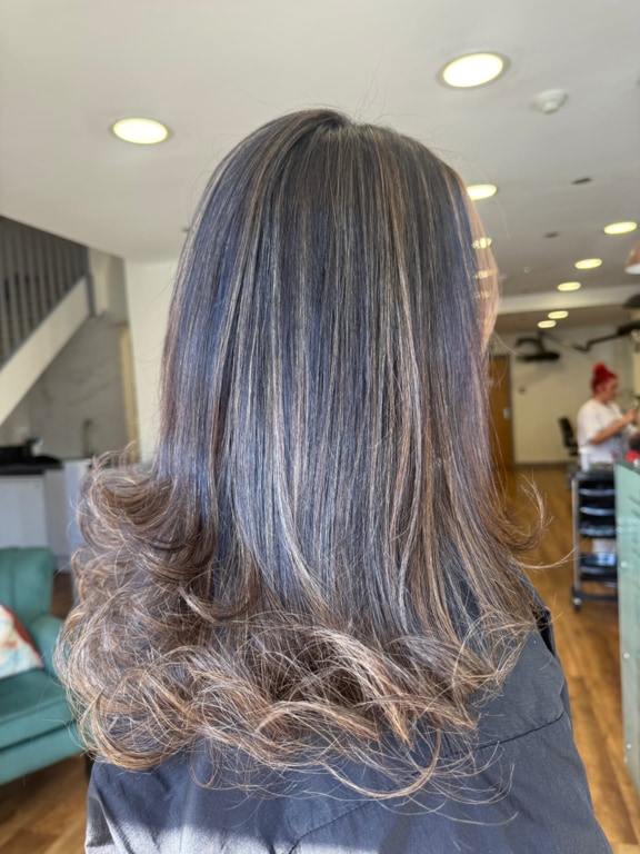 Dark brunette with lived-in highlights and curled ends, coloured at Thatchairs Hair & Body