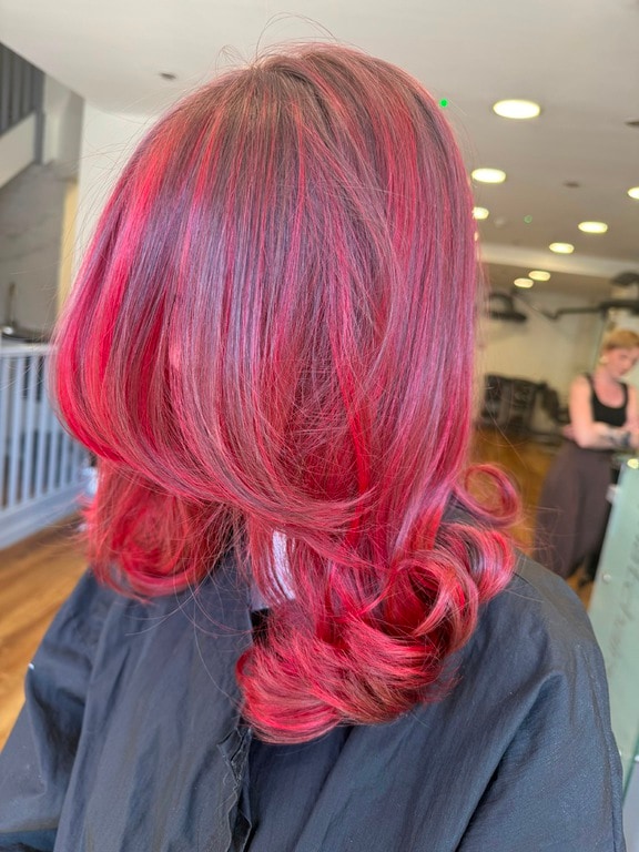 Vibrant red and pink colour with curled ends, coloured at Thatchairs Hair & Body